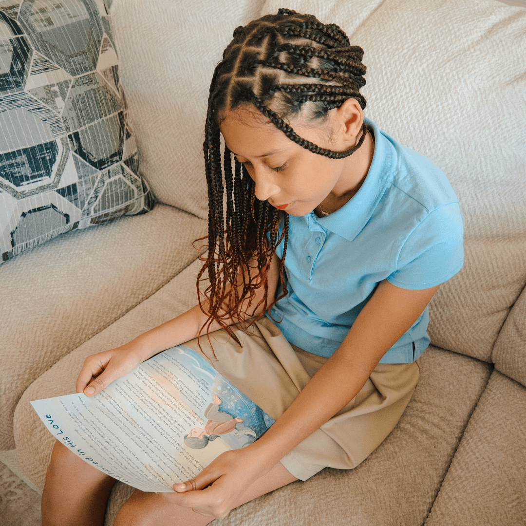 A girl reading a book while sitting on a couch