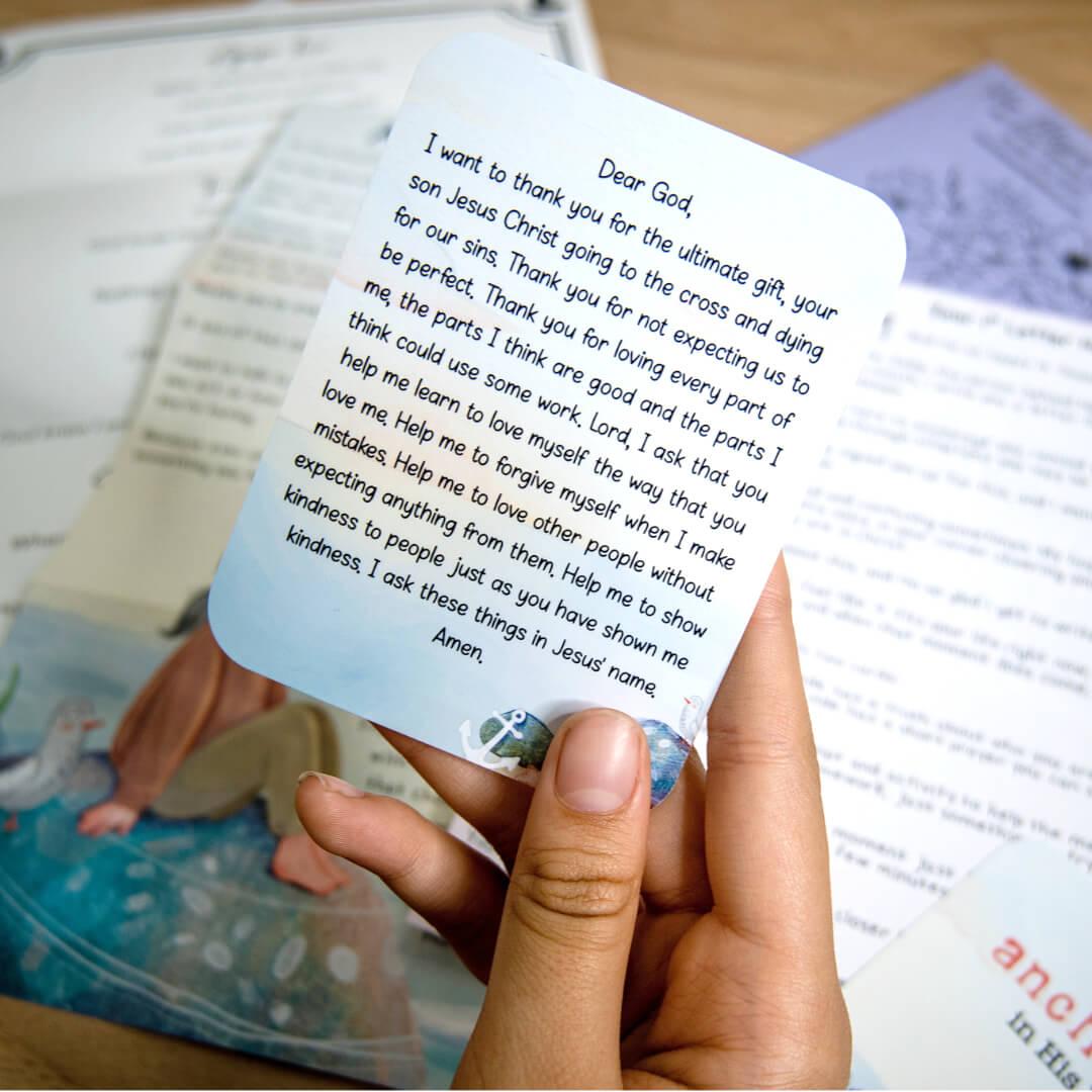 A handwritten prayer card held over a collection of letters