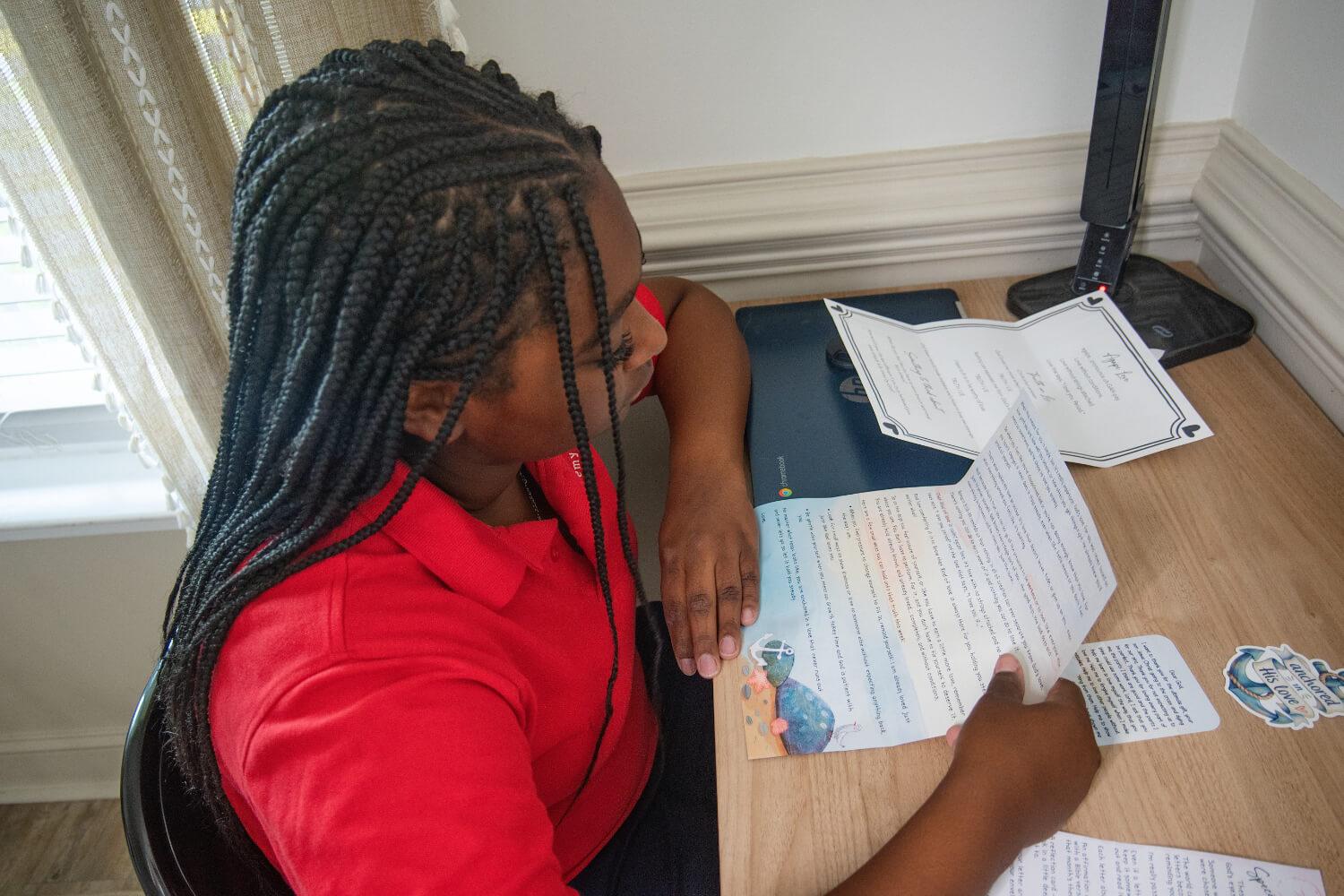A girl reading her Her Blessed Letter at a desk
